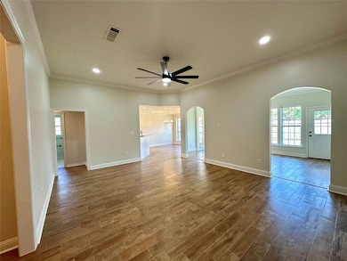Empty room featuring crown molding, arched walkways, wood finished floors, ceiling fan, and recessed lighting