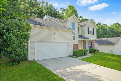 Traditional-style home featuring driveway, brick siding, a shingled roof, a front yard, and an attached garage