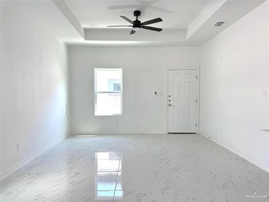 Unfurnished room featuring a raised ceiling, ceiling fan, and light marble finish flooring