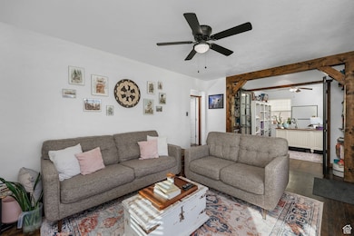 Living room featuring wood finished floors, ceiling fan, and beam ceiling