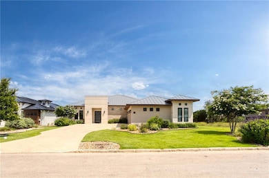 Contemporary home with a standing seam roof, a front yard, metal roof, driveway, and stucco siding