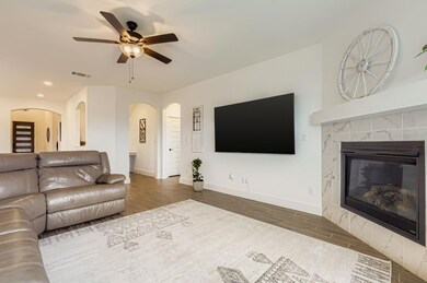 Living room with wood finished floors, ceiling fan, recessed lighting, a fireplace, and arched walkways
