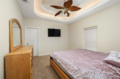 Bedroom with carpet floors, ceiling fan, and a raised ceiling