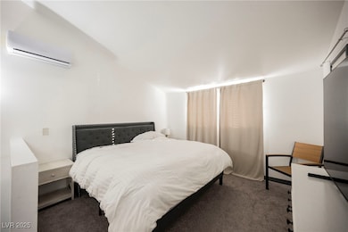Bedroom featuring carpet floors and an AC wall unit