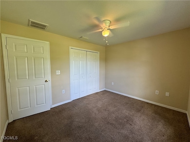 Unfurnished bedroom with dark carpet, a closet, and a ceiling fan