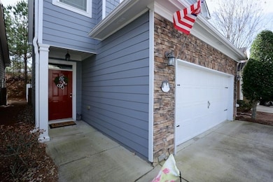 Entrance to property featuring stone siding, concrete driveway, and a garage