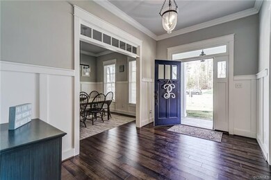 Gracious foyer with hardwood floors, wainscoting a