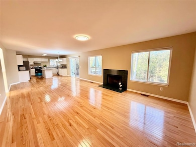 Unfurnished living room featuring a fireplace, a chandelier, and light wood-type flooring