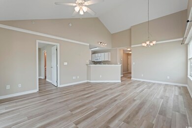 Unfurnished living room featuring high vaulted ceiling, ceiling fan, a chandelier, light wood-style flooring, and baseboards