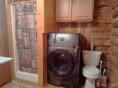 Full bathroom featuring a stall shower, washer / dryer, wooden walls, rustic walls, and vanity