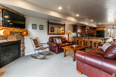 Carpeted living area featuring a fireplace, bar with sink, a textured ceiling, and recessed lighting