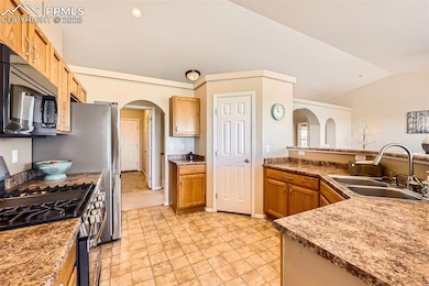 Kitchen featuring stainless steel range with gas cooktop, microwave, arched walkways and lofted ceiling
