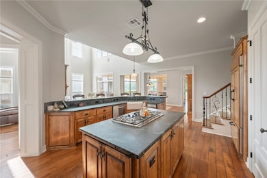 Kitchen with brown cabinets, dark countertops, sta