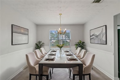 Tiled dining area featuring a chandelier, a textured ceiling, and baseboards