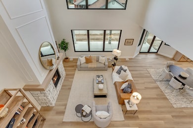 Living area with a lit fireplace, light wood-style floors, and a towering ceiling