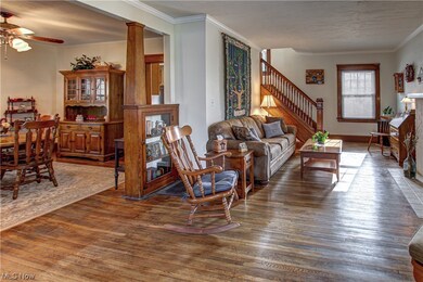 Family room with dark hardwood / wood-style floors, ceiling fan, and ornamental molding