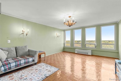 Living room with crown molding, a chandelier, and radiator