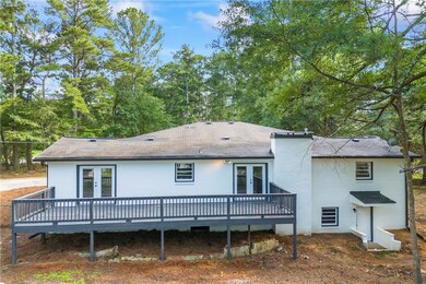 Rear view of house featuring french doors, a wooden deck, and roof with shingles