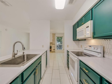 Kitchen with white appliances, green cabinets, a 