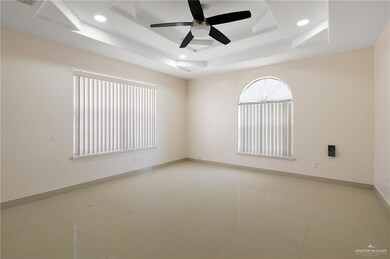 Empty room with a ceiling fan, baseboards, a tray ceiling, light tile patterned flooring, and recessed lighting