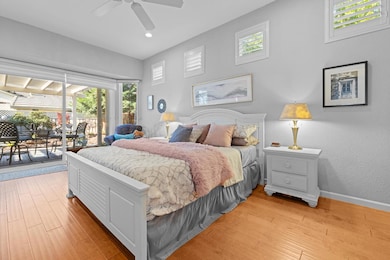 Primary bedroom with multiple windows, access to outside, light wood-style flooring, and a sunroom