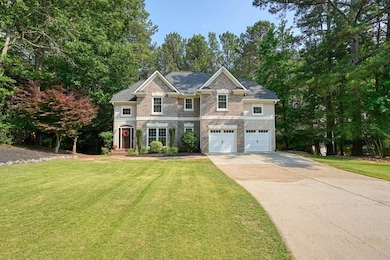 View of front of property featuring concrete driveway, a front yard, an attached garage, and view of wooded area