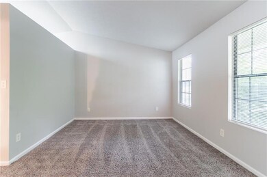 Spare room with carpet flooring, baseboards, and vaulted ceiling