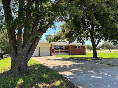 Single story home with brick siding, an attached garage, driveway, a front yard, and a porch