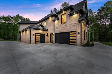 Property exterior at dusk with concrete driveway, brick siding, and an attached garage