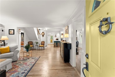 Living room with light wood-type flooring, ornamental molding, and stairs