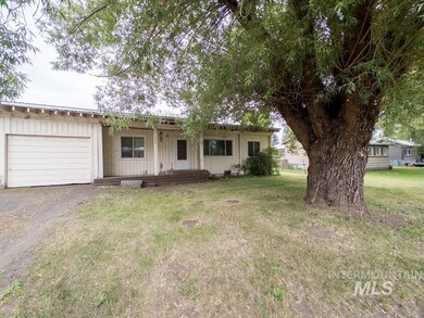 Ranch-style home featuring a garage, board and batten siding, a front lawn, and driveway