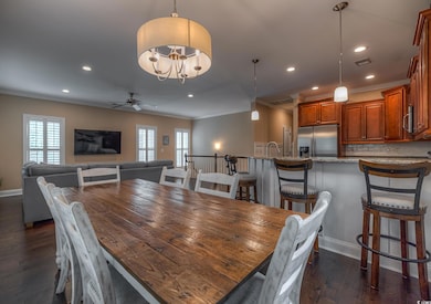 Dining space with crown molding, dark wood-type flooring, recessed lighting, ceiling fan, and a chandelier