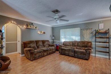 Living room with crown molding, ceiling fan, a tex
