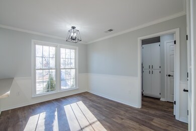 Spare room with crown molding, dark wood-type floo
