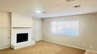 Unfurnished living room with a brick fireplace and light colored carpet