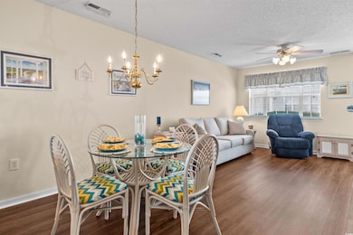 Dining space with dark wood finished floors, ceiling fan, a chandelier, baseboards, and a textured ceiling