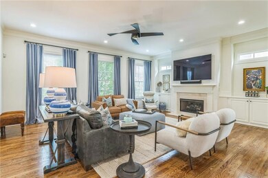 Living room featuring crown molding, wood finished floors, ceiling fan, a premium fireplace, and recessed lighting, so much room to entertain or relax. The upgrades and updates are spectacular!