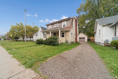Bungalow-style home featuring a gambrel roof, covered porch, an outdoor structure, a front lawn, and a garage