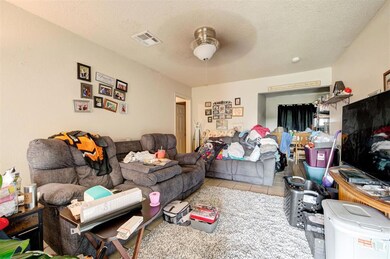 Tiled living room with ceiling fan and a textured 