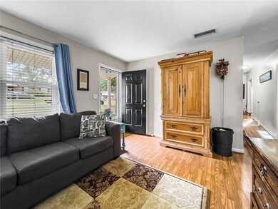 Living room featuring visible vents, light wood fi