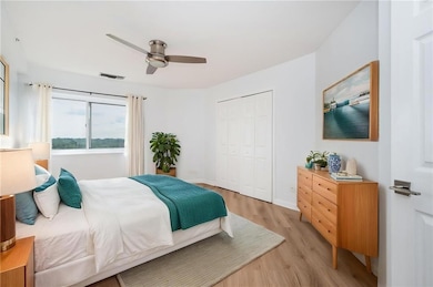 Bedroom featuring light wood-type flooring, a closet, a ceiling fan, and baseboards, walk in closet