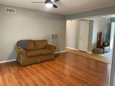 Den featuring ceiling fan, light wood-style flooring, and crown molding