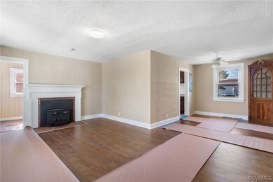 Unfurnished living room with dark hardwood / wood-style floors, a fireplace, ceiling fan, and a textured ceiling
