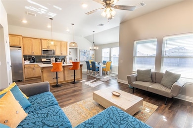Living room with lofted ceiling, dark hardwood / wood-style floors, and ceiling fan with notable chandelier