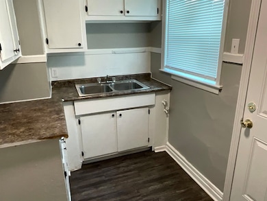 Kitchen with baseboards, white cabinetry, dark cou
