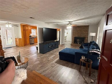 Living room featuring ceiling fan, wood finished floors, a textured ceiling, and a fireplace