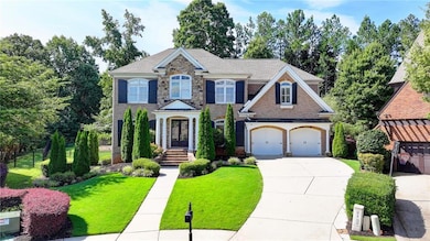 Georgian-style home with driveway, a front yard, a garage, stone siding, and a shingled roof
