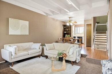 Living area with beamed ceiling, beverage cooler, stairway, ceiling fan, and carpet floors