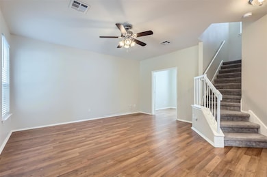 Empty room with stairs, ceiling fan, visible vent