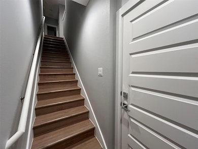 Stairway with wood finished floors and a textured wall